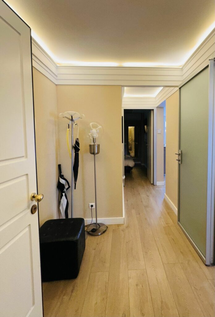 Couloir intérieur avec parquet clair, éclairage LED, portes coulissantes vertes – appartement location Monaco