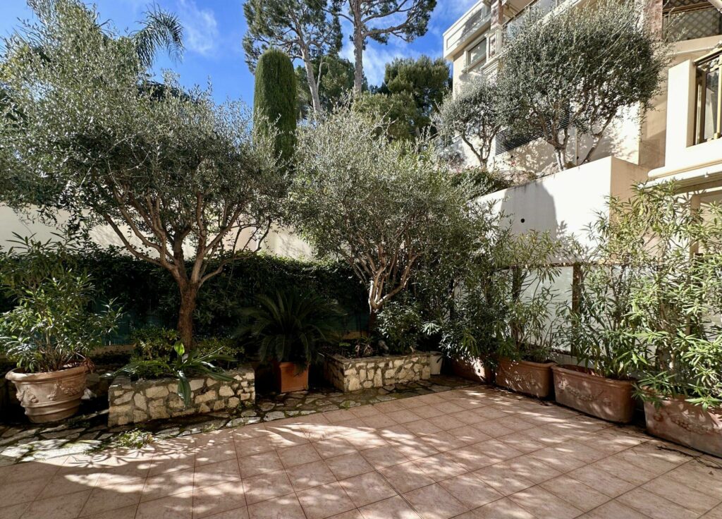 Jardin carrelé avec oliviers, vue sur la façade de l'immeuble – location saisonnière Cap d'Ail